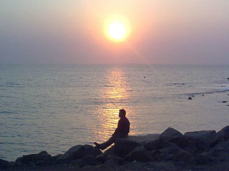A visitor enjoying the sunset at Pirwadi Beach