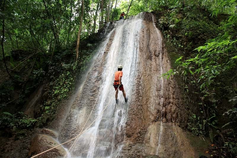 An adventure enthusiast crappeling on the slippery slopes of the waterfall